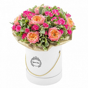 Пионовидные и кустовые розы с зеленью в шляпной коробке